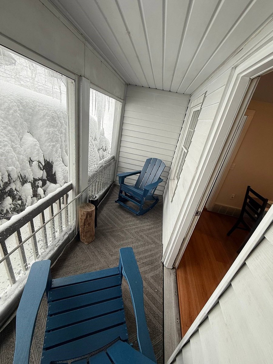 Peaceful screened in front porch with rocking Adirondack chairs.