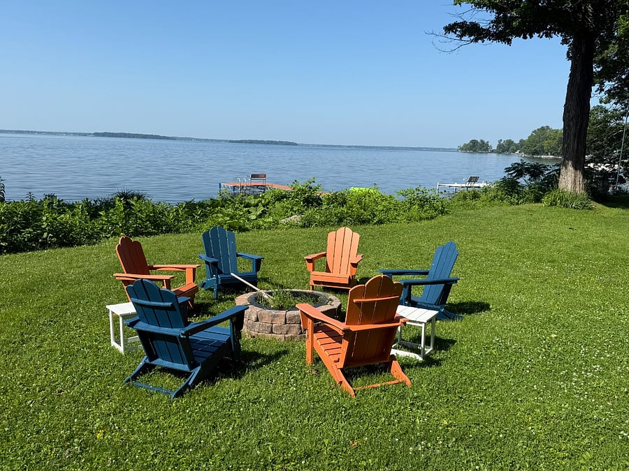 Fire pit with Adirondack chairs and tables for s'mores. 