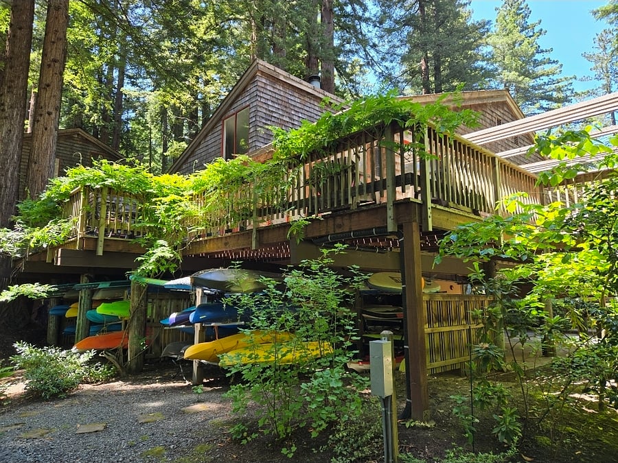 The cub house deck overlooks the Russian River. Below, there are racks for kayaks and paddleboards.