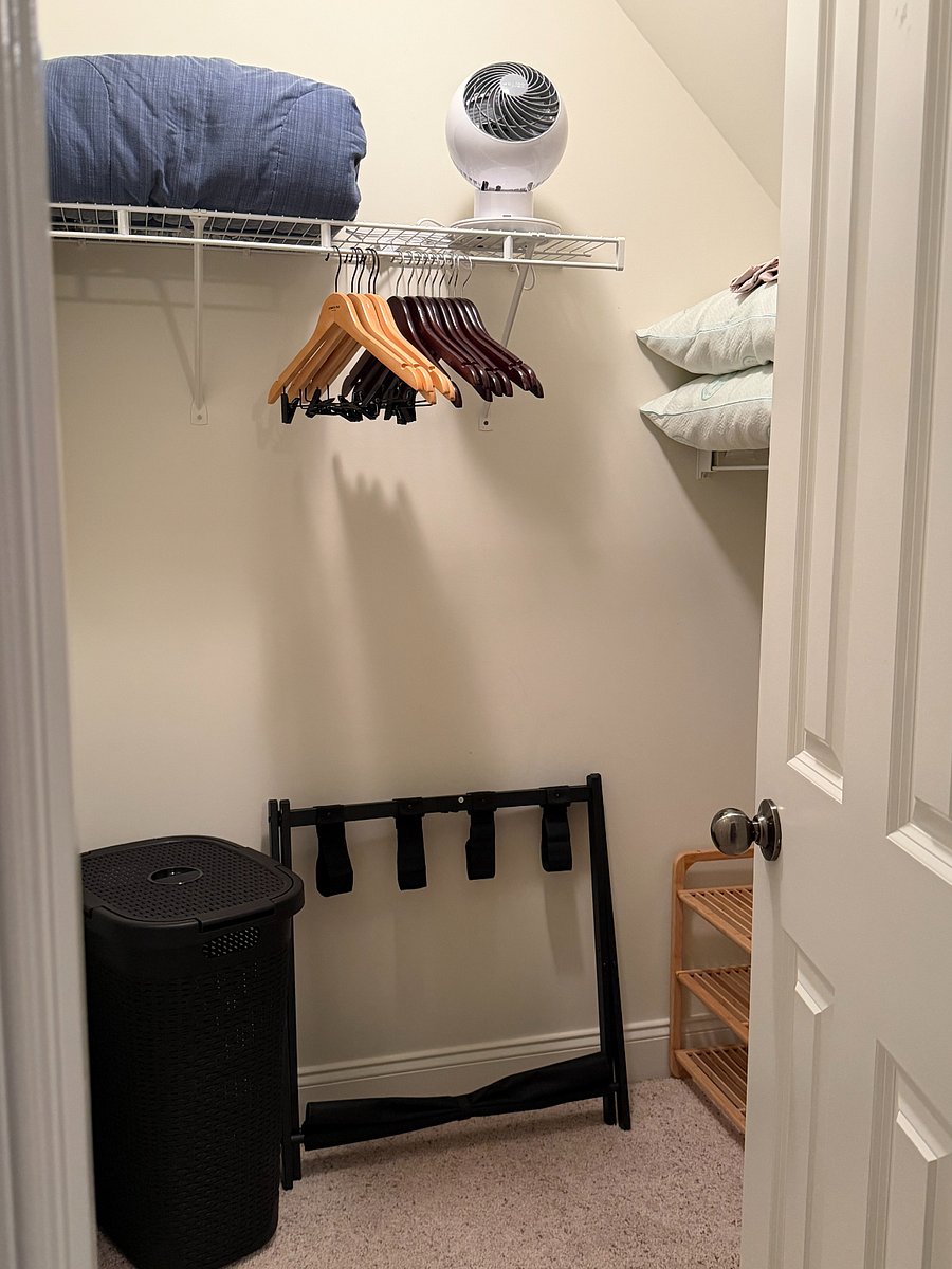 Walk-in closet with hangers, storage space, extra linens, and fan for comfort.
