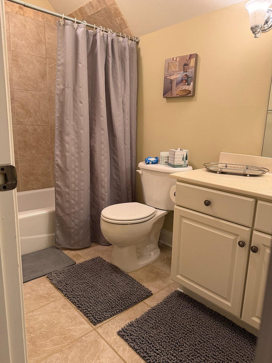Tub and shower combination with fresh towels and essential toiletries.