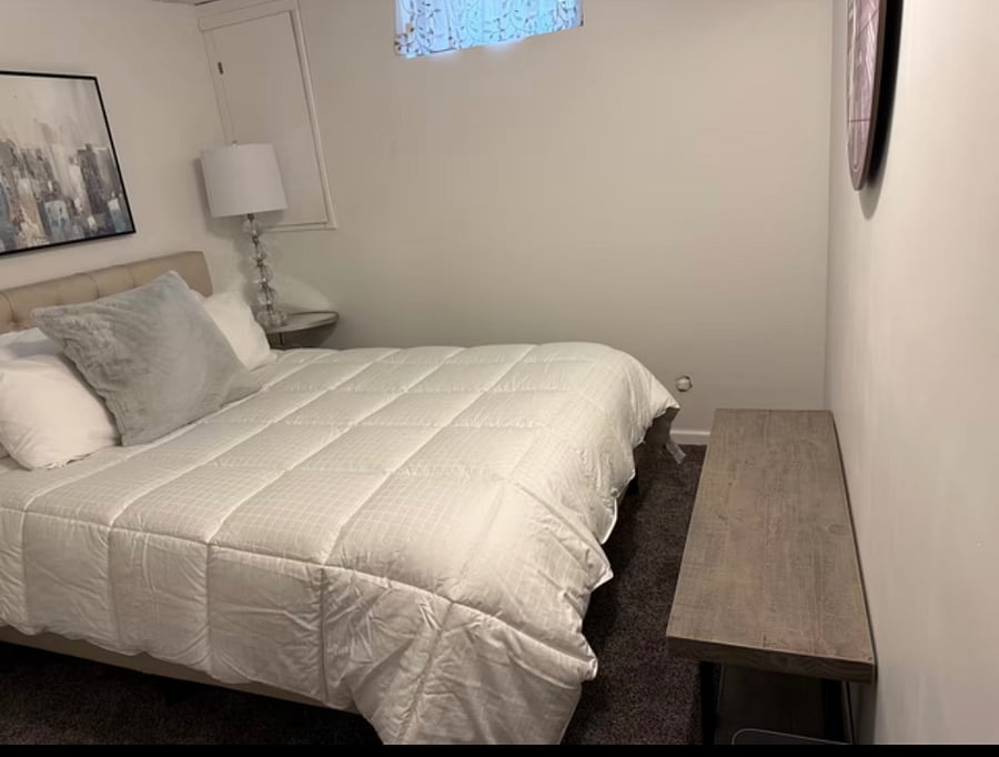 Bedroom 4 in basement has Luxury Queen Size Bed, closet cabinet, lamps, bench, and chair.