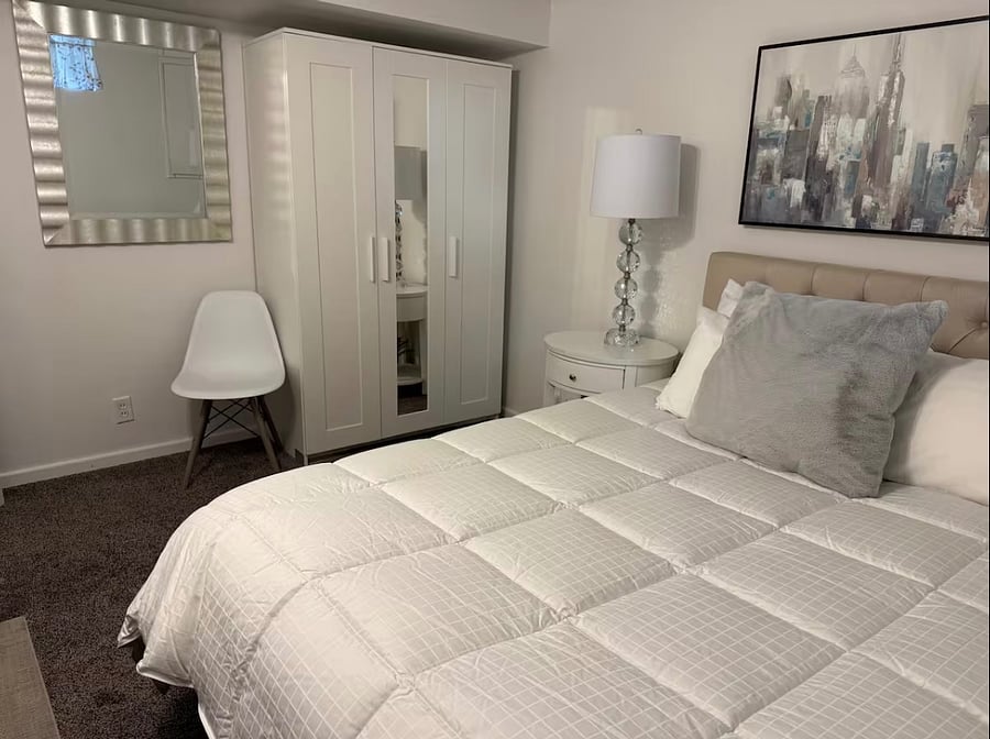 Bedroom 4 in basement has Luxury Queen Size Bed, closet cabinet, lamps, bench, and chair.