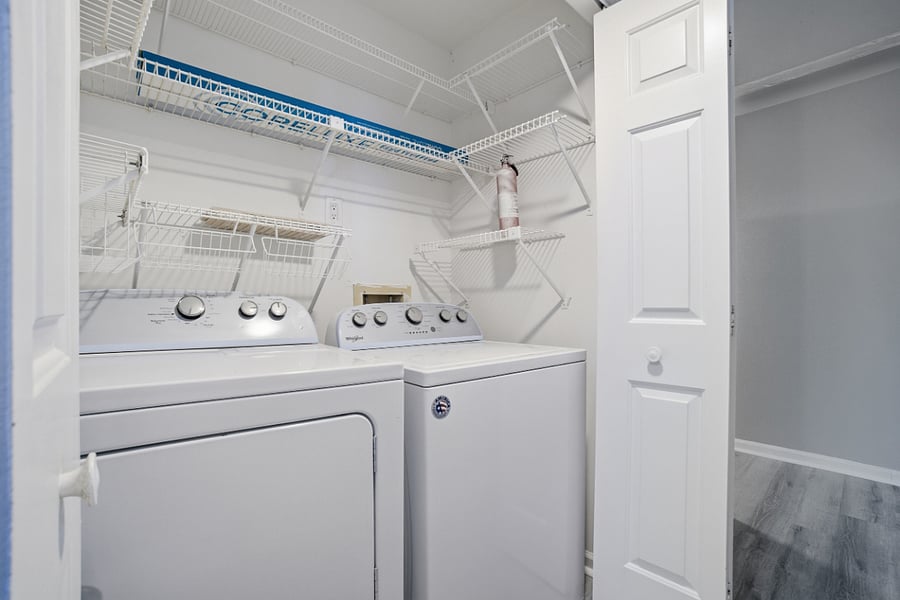 Laundry with Full size washer and dryer and storage shelving.