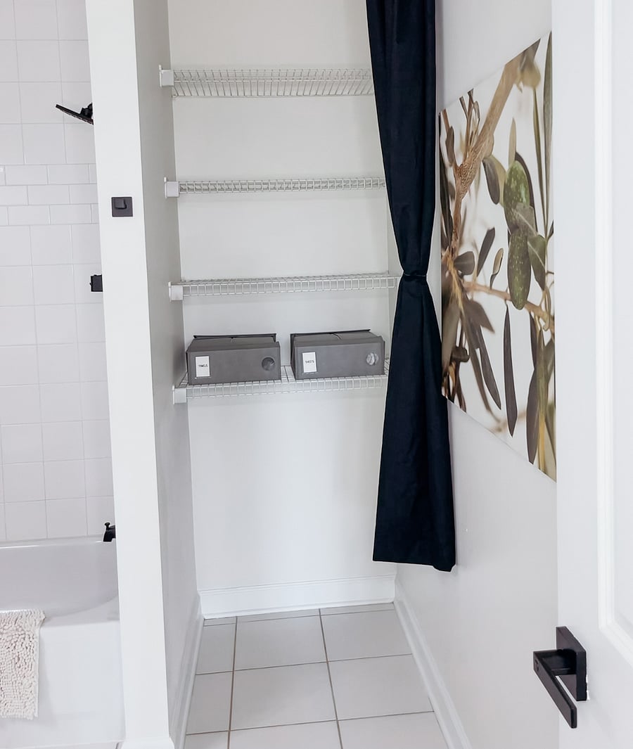 Ample storage shelving with privacy curtain in the bathroom line closet