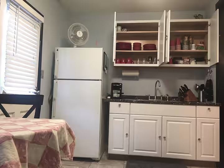 Kitchenette with full-size refrigerator, coffee maker, dishes, and sink.