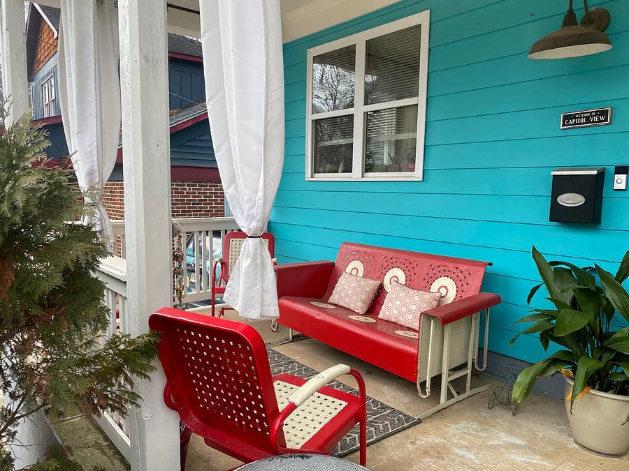 Front porch with glider set behind large shrubs/secluded from street