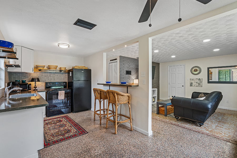 Full view of kitchen, bar and stools, and living room.