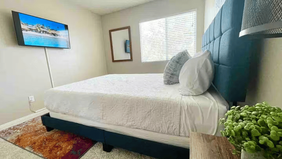 Third bedroom featuring a queen-size bed, wall-mounted Smart TV, and natural light ideal for long-term guests.