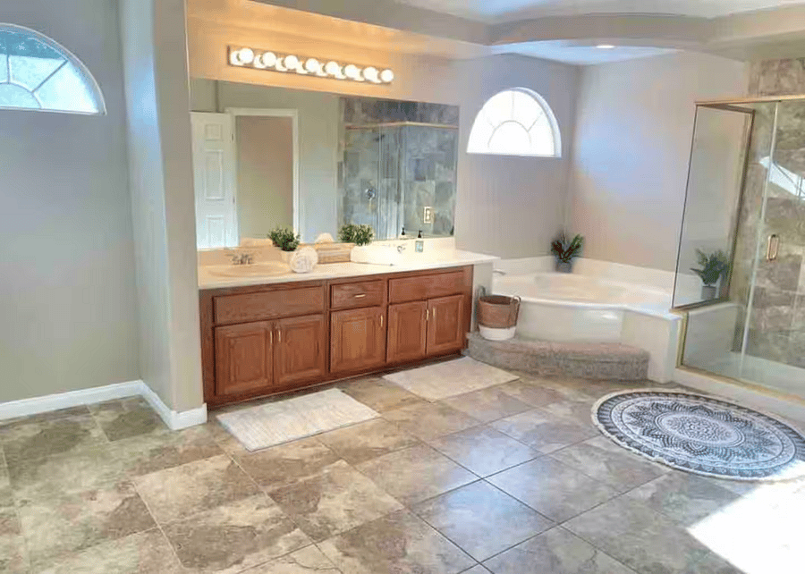 Spacious primary en suite bathroom designed for comfort and ease. Features a dual-sink vanity, large mirrors, and generous counter space. Enjoy a soaking tub, separate glass-enclosed shower, and abundant natural light for a spa-like experience.
