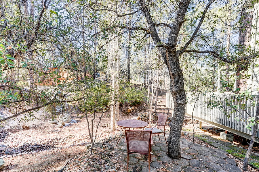 Outdoor round table with two chairs under a shaded tree.
