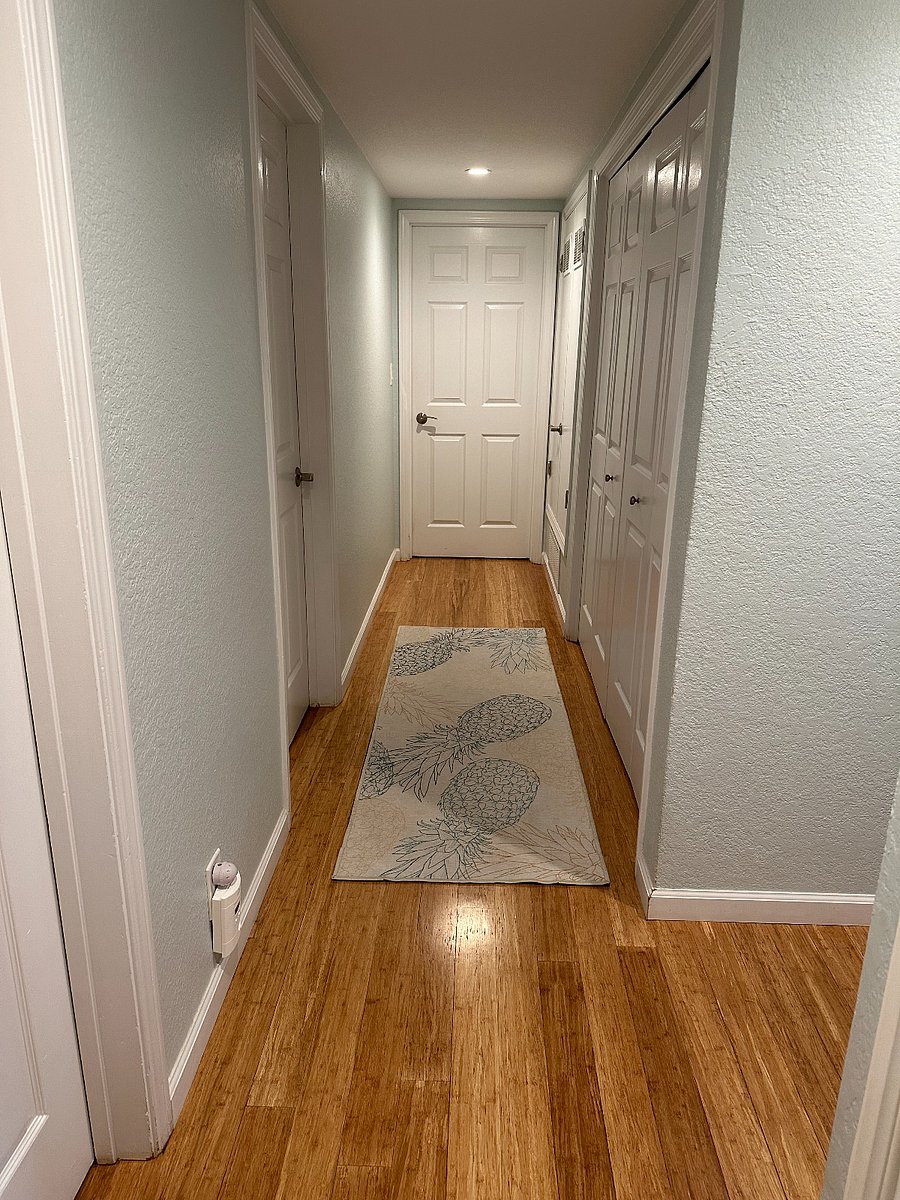 Hallway with laundry room to the right and remaining two bedrooms