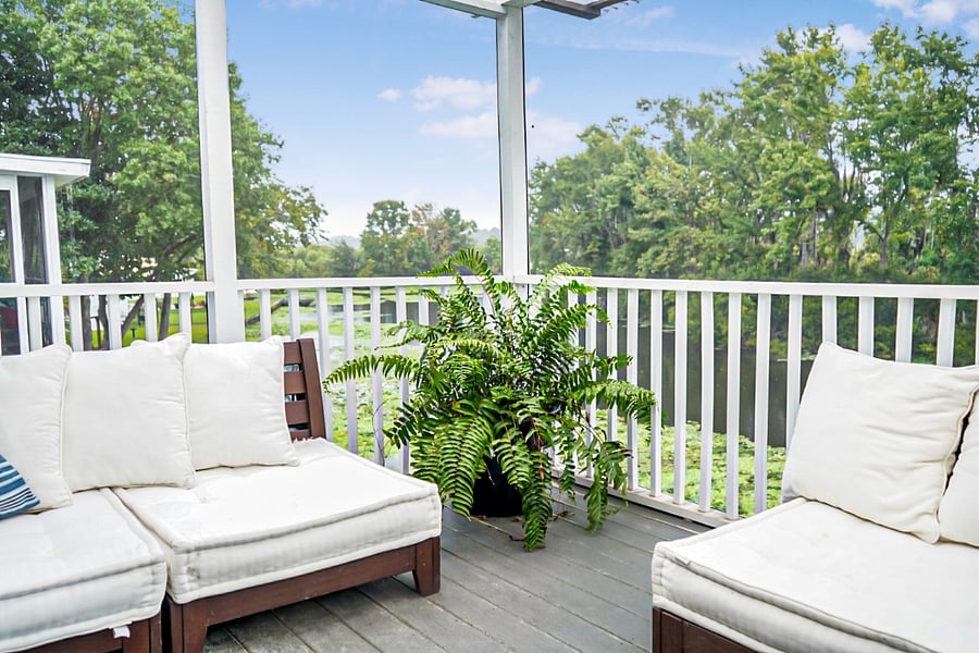 Relaxing balcony seating surrounded by greenery and peaceful water views.