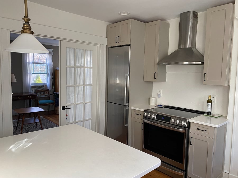 Kitchen with office in background. Island with four stools. 