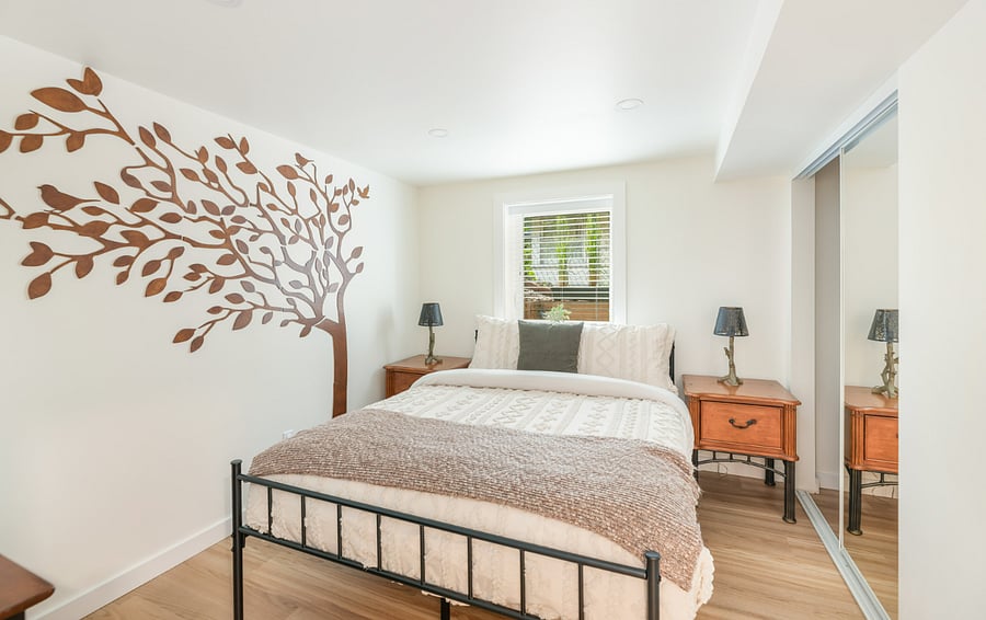 The Tree Room: 
- Back bedroom with gorgeous wall art and cozy bedding for restful nights  
- Bright natural light through the window creates a calm vibe  
- Simple modern design with bedside tables, reading lamps and a smart TV with  streaming channels.
