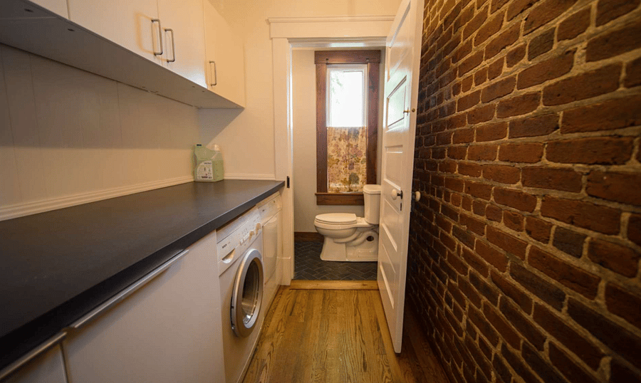 Exposed brick hallway to washer, dryer and half bath.