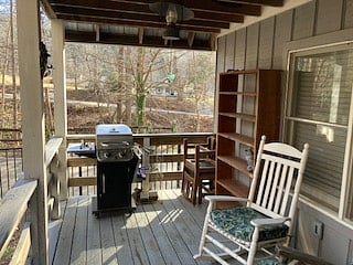 The porch has a gas grill, two rocking chairs, a shelf unit, and a dining table with 3 chairs.