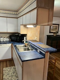 View to kitchen, with showing appliances and modern cabinets. The kitchen borders on the living room, and dining area, with a two seated bar between. There is seating for 5 in the dining room.