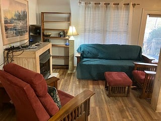 The living room has a full-length sofa, two easy chairs (a recliner, and rocker with Ottoman). There is a propane fireplace providing comfortable cozy heat, controlled by thermostat. There are blinds for the double windows for privacy.
