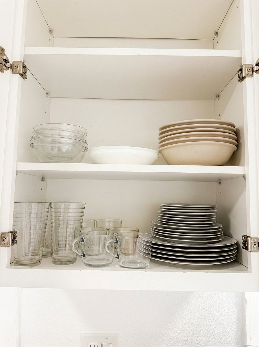 Stocked kitchen cabinets with dishes, glassware, and cookware