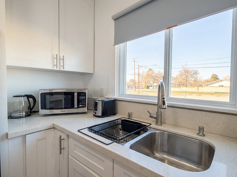 Kitchen workspace with microwave, kettle, and natural light