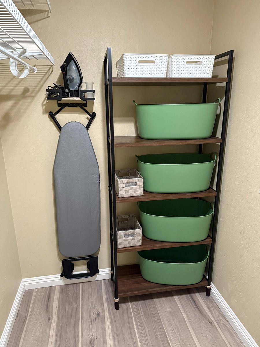 One end of closet with ironing board & baskets for storage - one of the baskets has spare linen