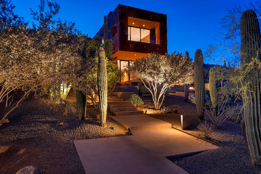 Twilight arrival at a private architectural retreat, set high among saguaros with dramatic desert lighting and complete seclusion.