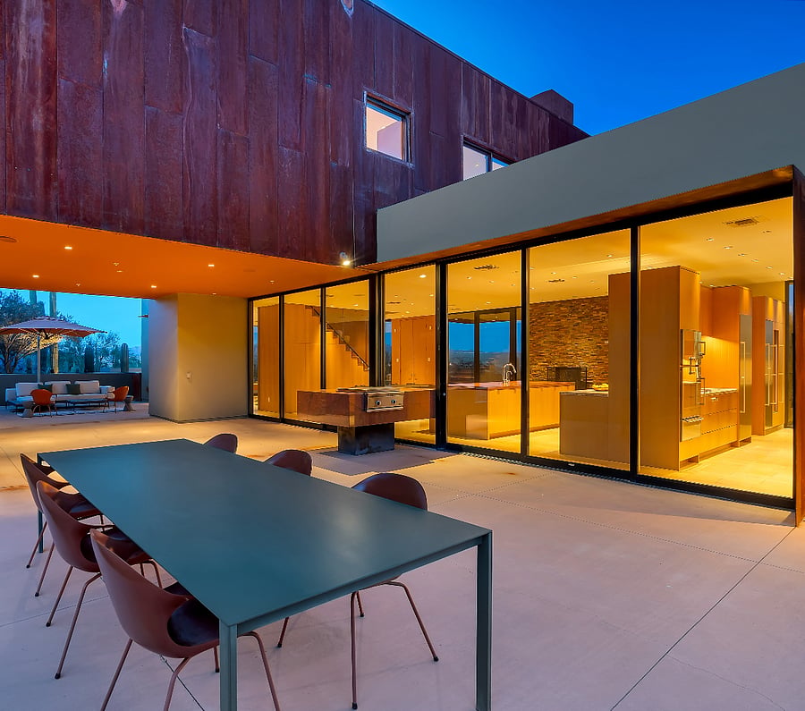 Evening entertaining terrace where warm interior light meets cool desert air for memorable nights.