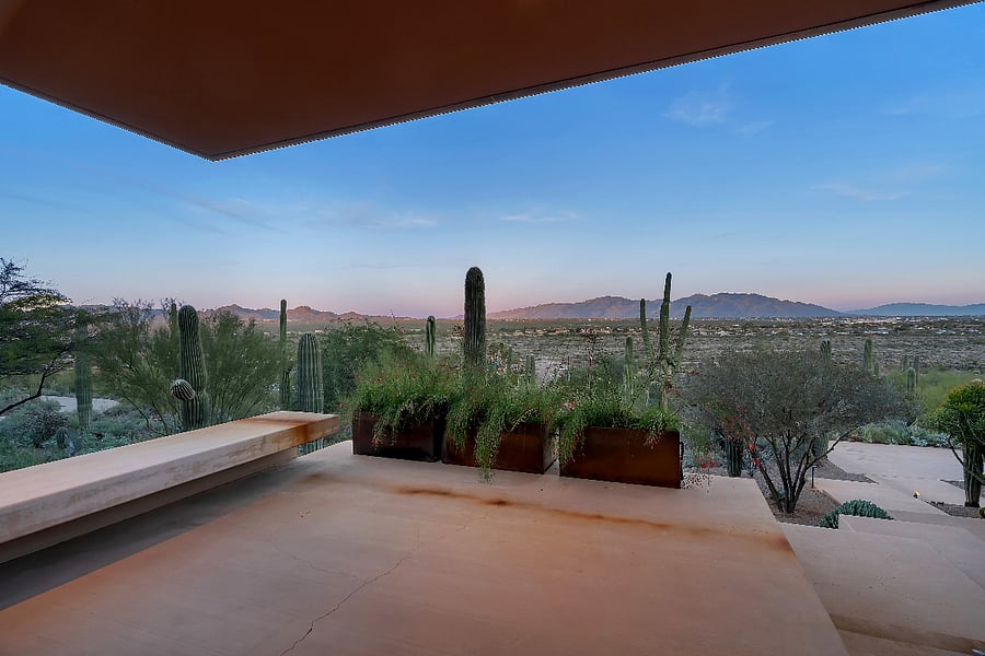 Sunset terrace overlooking protected saguaro forest and distant mountain ranges.