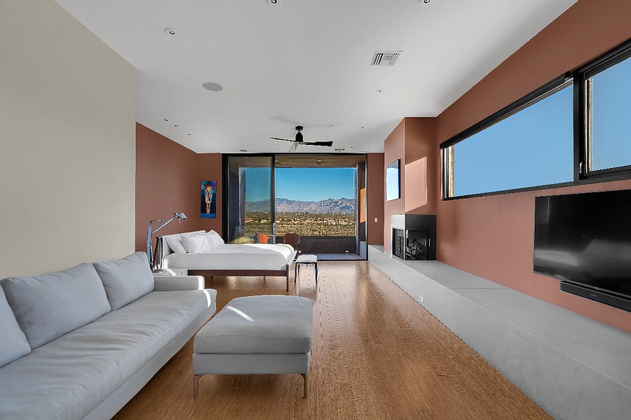 Primary suite with king bed, fireplace, lounge seating, and private terrace views.