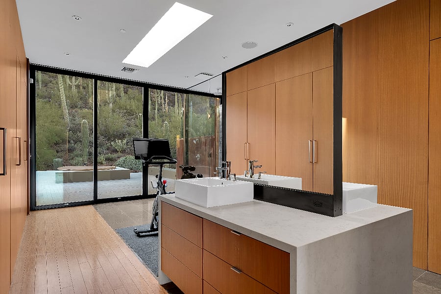 Primary bath vanity with dual sinks, custom millwork, and views into the surrounding desert.