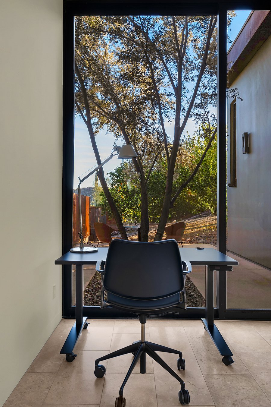 Dedicated work setup with sit-to-stand desk and calming garden views just outside the window.