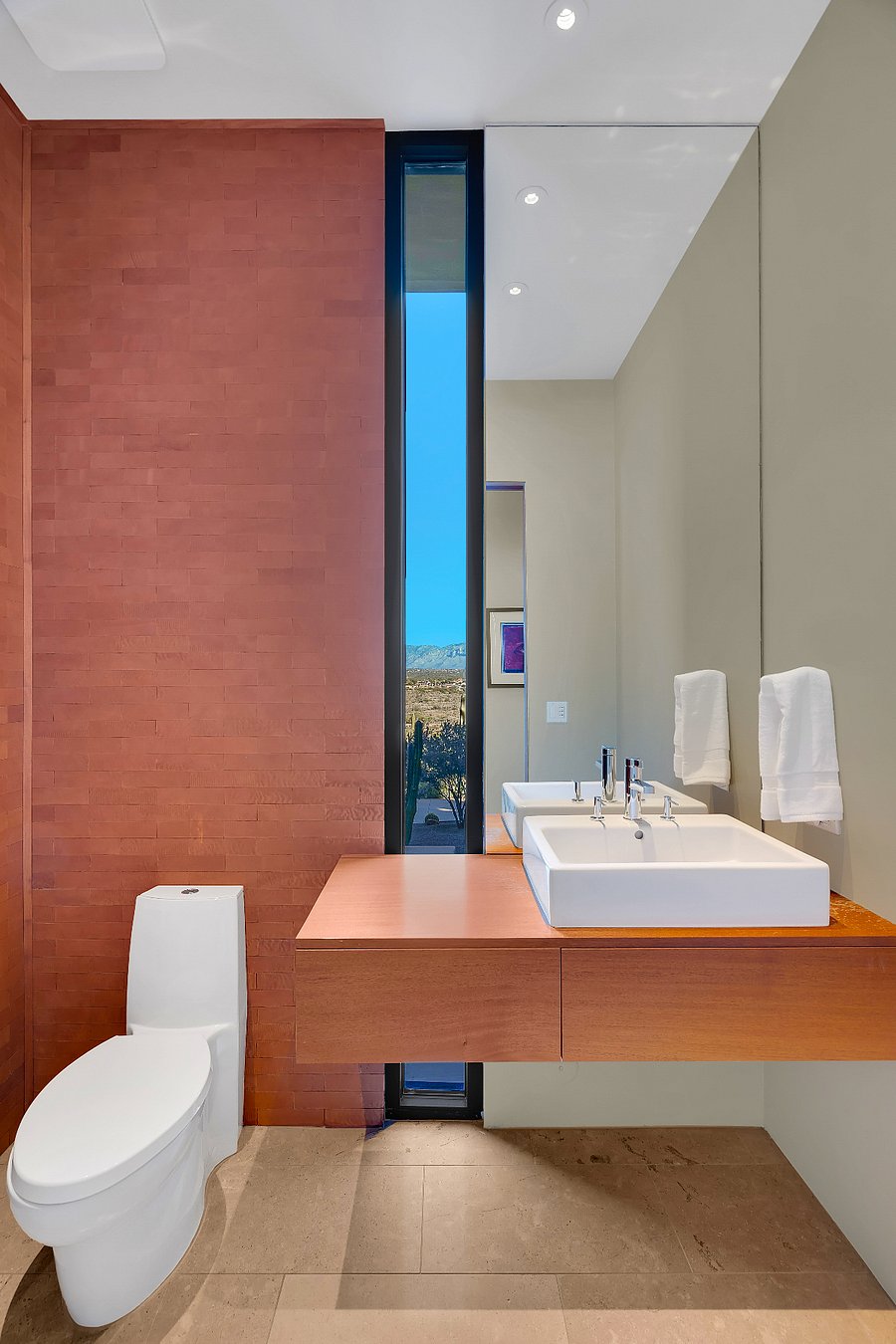 Half bath with modern fixtures, warm materials, and a vertical window framing mountain views.