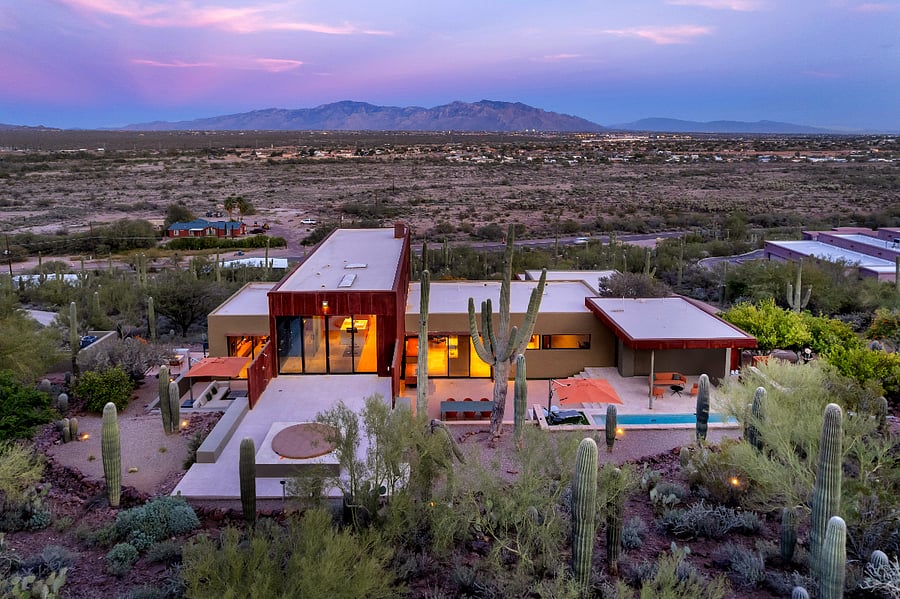 Elevated aerial view showing the full layout of the property, including terraces, pool and spa, and expansive desert views stretching to the mountains beyond.