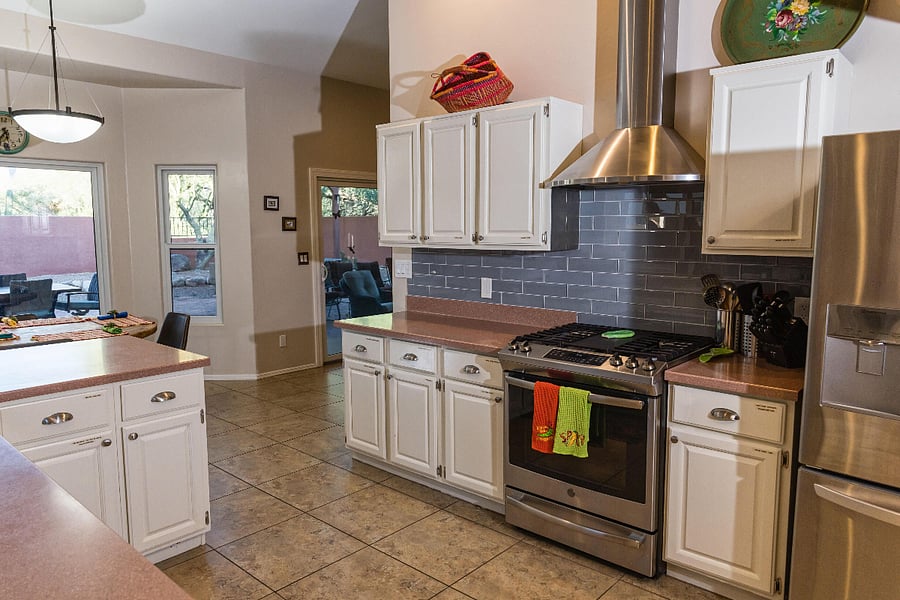 Kitchen with vent hood, gas stove and oven, sharp knives and utensils for cooking.