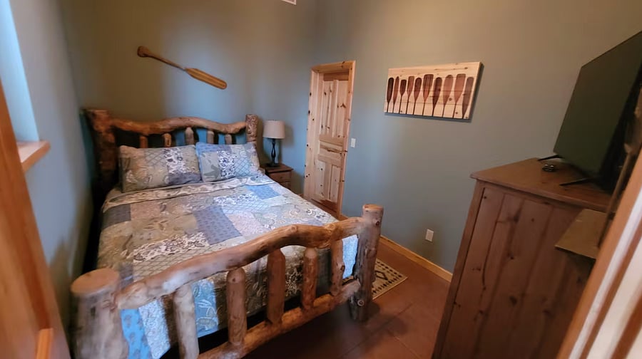 Guest bedroom with a queen bed and smart TV.