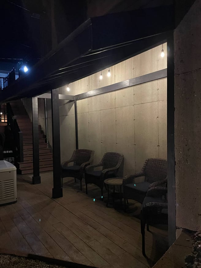 Covered patio with seating and string lighting.