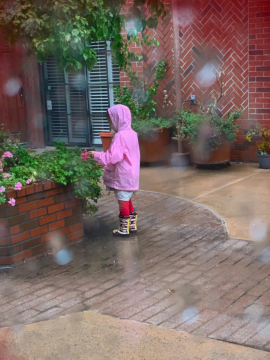 One of the neighbor children enjoying the courtyard flowers in the rain.