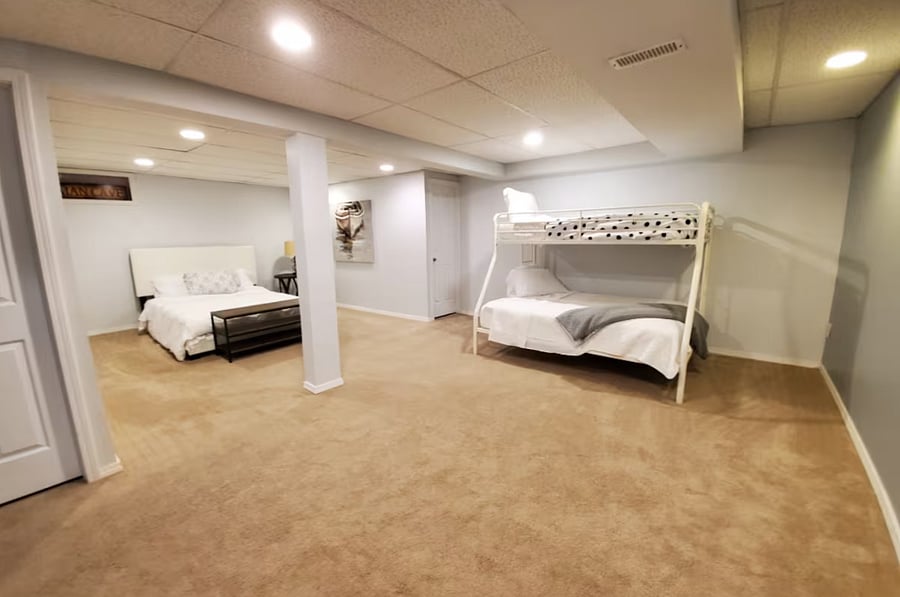 Finished basement with additional sleeping space featuring a full bed and bunk bed.
