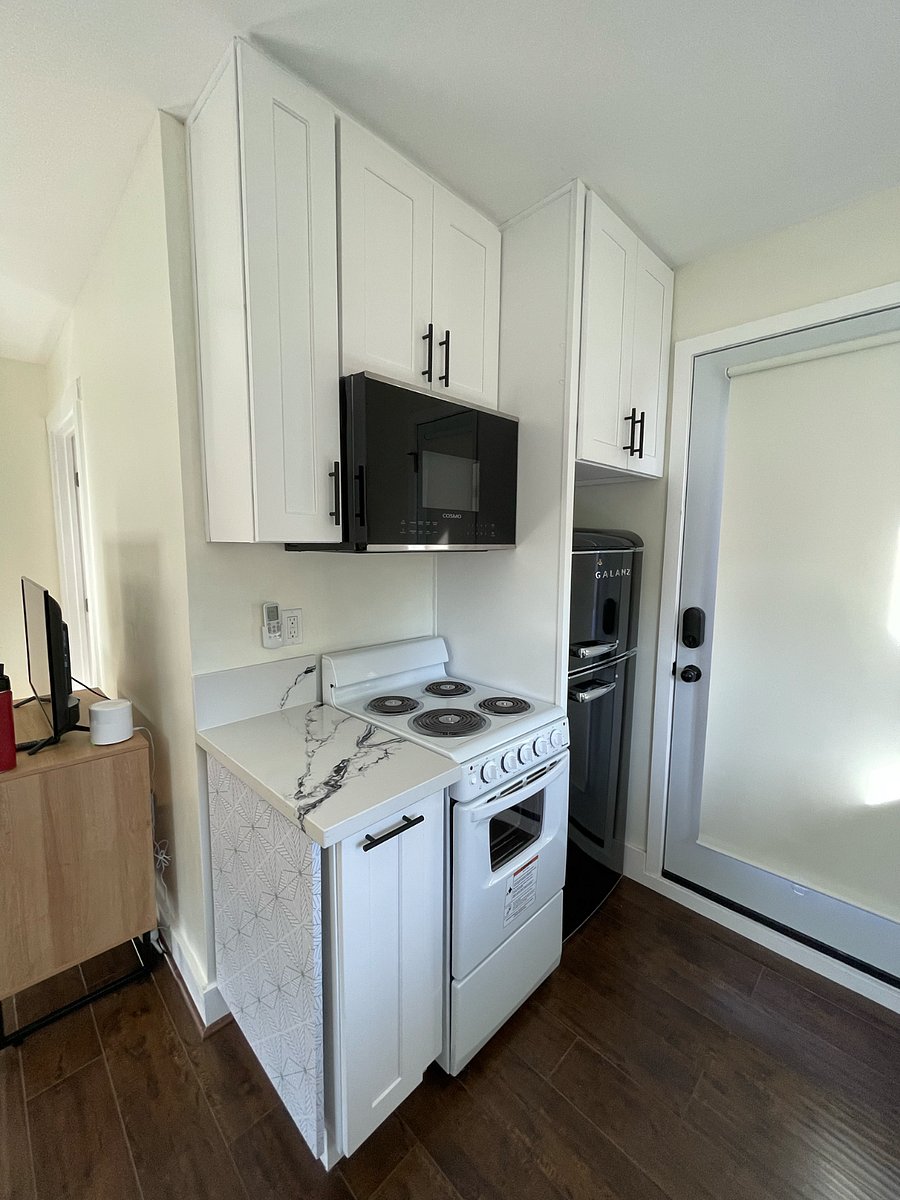 Upper cabinets for storage, microwave, and electric range w/ oven and four burners.