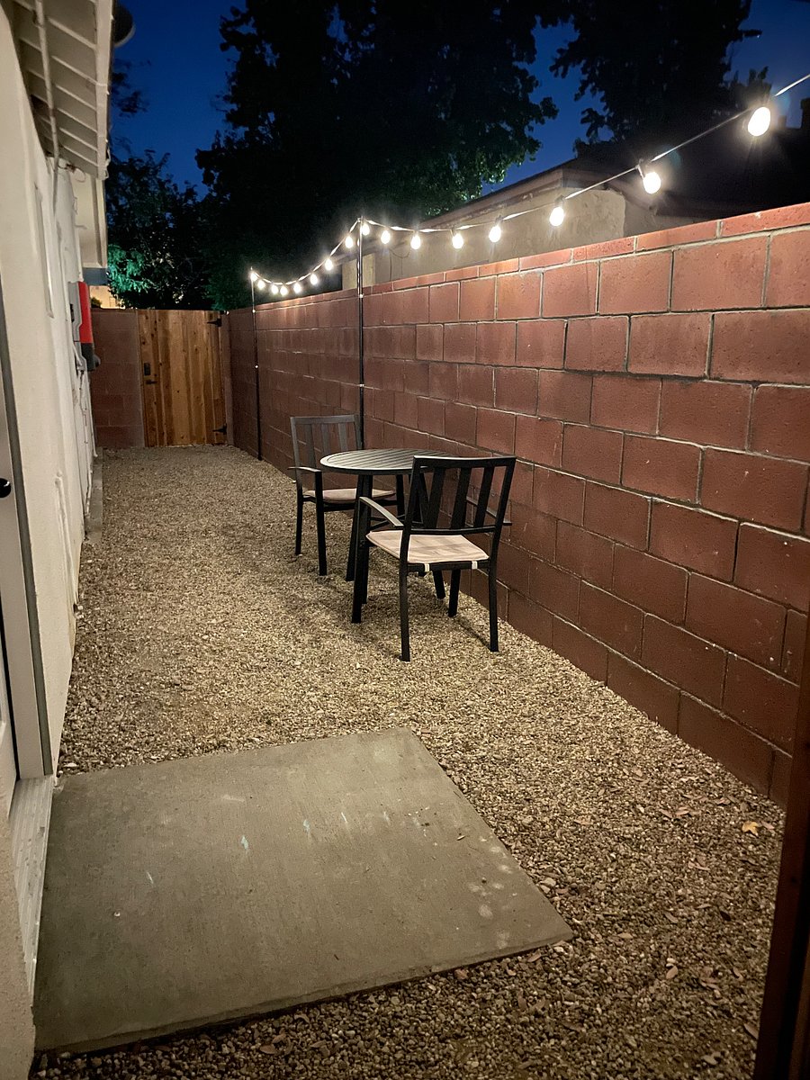 Private outdoor space with table, chairs, and solar string lights.
