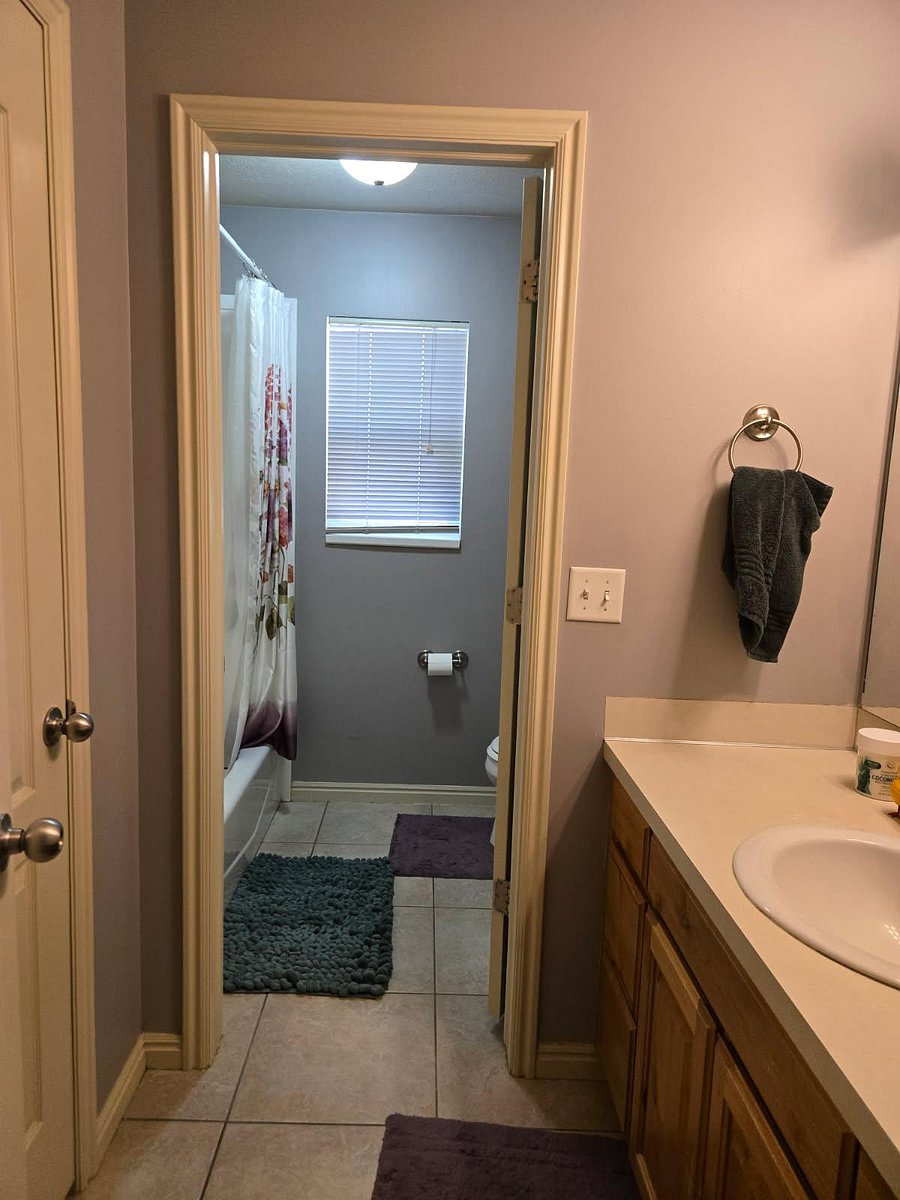 Shared bathroom with tub/shower and toilet separated from vanity and sink.