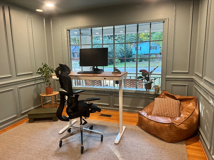 Dedicated office space, electric standing desk, monitor, keyboard, and mouse.