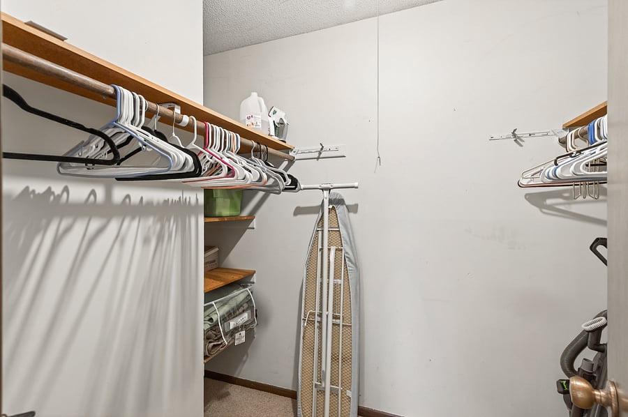Good size walk-in closet in the master bedroom featuring extra shelves for storage, iron, full size ironing board, steamer.