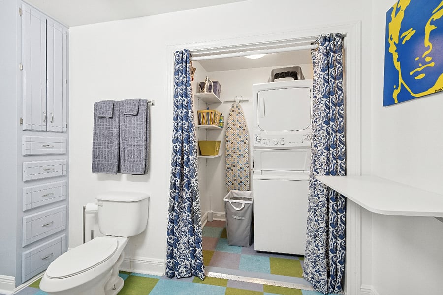 The updated bathroom includes a wash/dryer and a folding table for laundry.