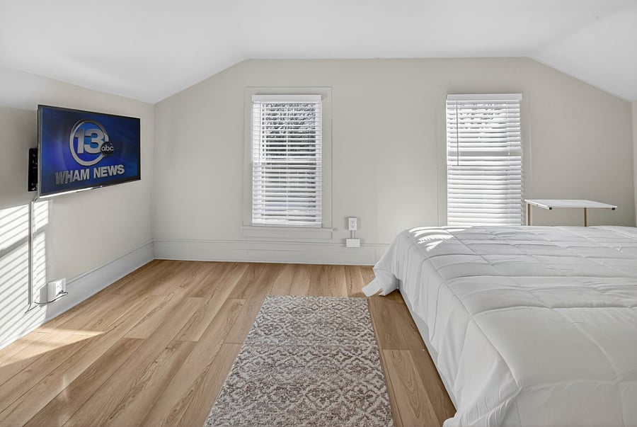 Bedroom 3 entails a wall-mounted Smart TV and queen bed with convenient side table.