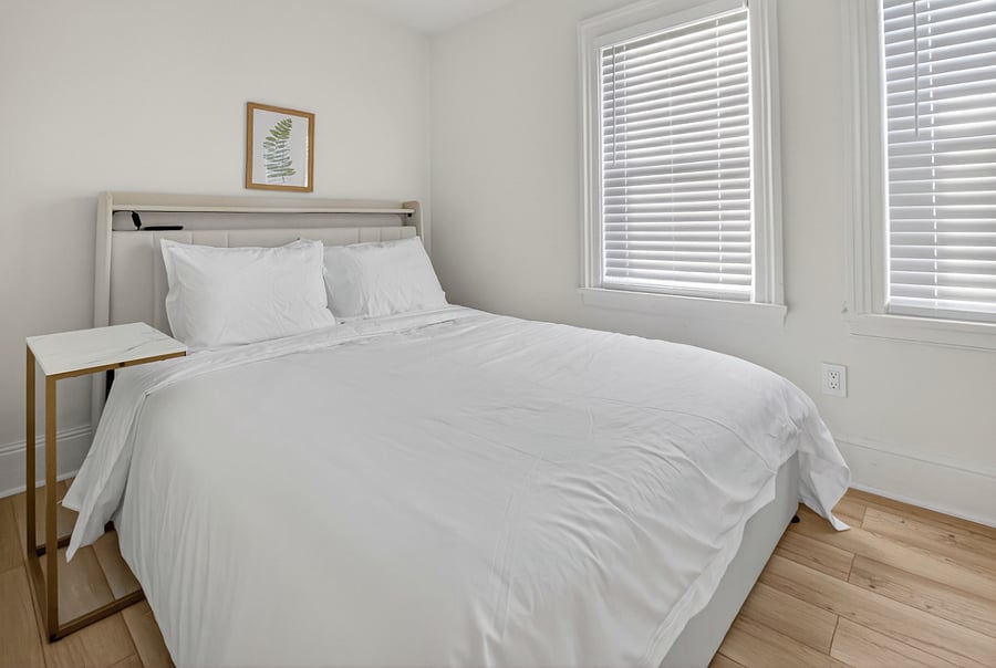 Bedroom 1 features a queen bed with an LED light frame, underbed storage, and a side table, creating a cozy and inviting space for a comfortable stay.