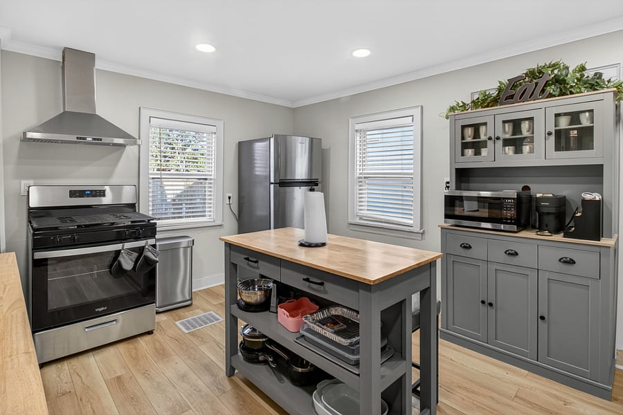 Kitchen view featuring the stove and range, stocked chefs table, refrigerator, and a dedicated microwave/air fryer, Nespresso coffee and tea bar.