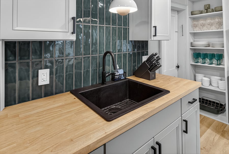 The kitchen features a deep sink with butcher board countertops and a full Henckels knife set, offering both style and functionality for meal preparation.