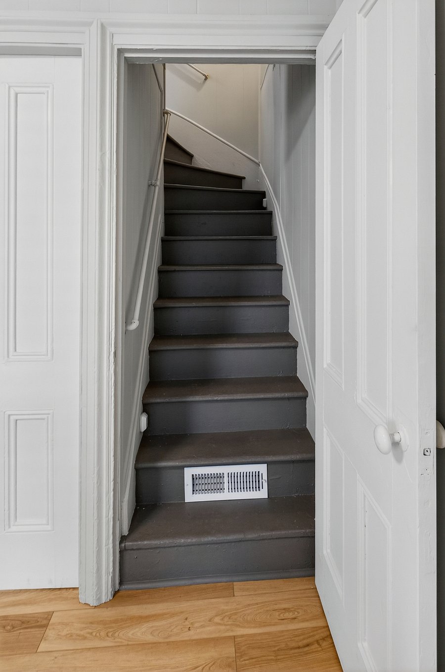 A short, steep staircase leads to the two upstairs bedrooms with a banister.